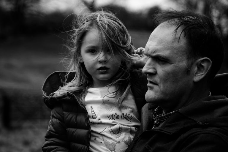 Black & white image of Dad and daughter on a windy day outside