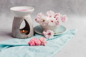Image of handmade soy wax melts with a burner and flowers on a grey stone backdrop
