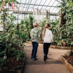 Two children walking among plants in a glasshouse