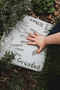 Childrens hands in Grandads handprint in a cement stone