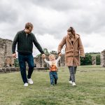 Family walking hand in hand among ruined abbey