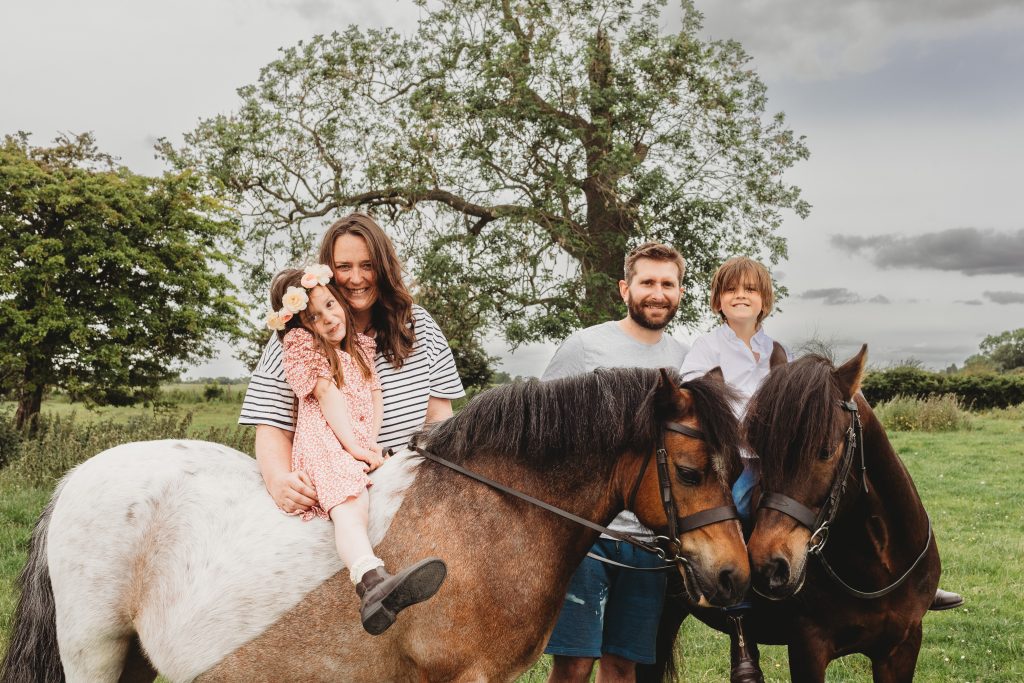 Family of four family portrait with their ponies in a field