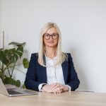 Working portrait of a corporate business women sitting at a desk wearing a suit.