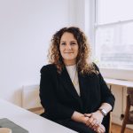 Working headshot of a business women sitting in an office.