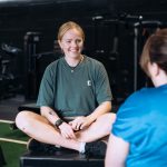 Photo of a female personal trainer chatting with a client in gym.