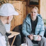 Photo of a female coach chatting with a client in a garden summer house.