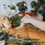 Close up of a florist tying ribbon round a bunch of flowers.