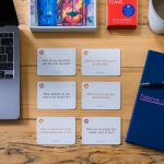 Coaching cards, diary and laptop laid out on a wooden desk for a business owner.