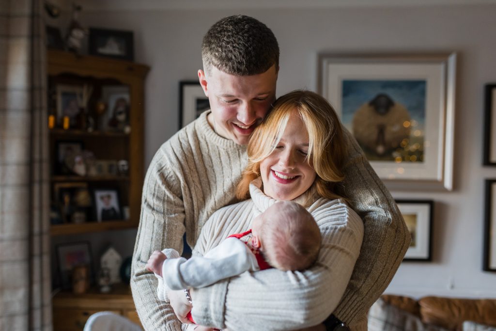 New parents holding their newborn baby at home