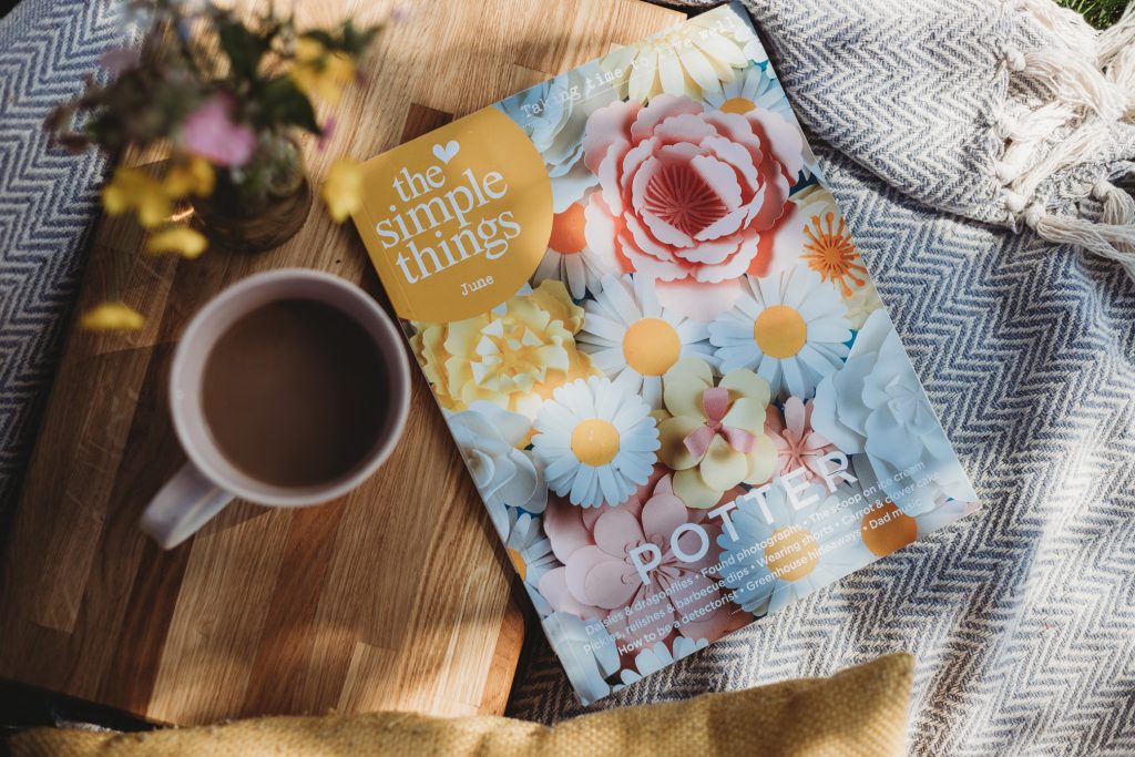 Photo of coffee and a magazine outside on a rug sepicting a simple way to rest or celebrate.