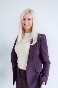 Headshot of a business women standing by a white office wall.