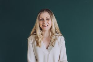 Headshot of a business women standing by a green office wall.