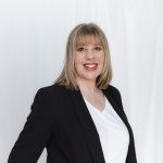 Studio headshot of a business women standing by a white wall