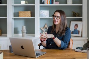 Brand photograph of a business women sitting at a desk in a homely office with her laptop.